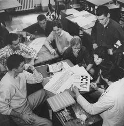students looking at print collateral black and white historical photo